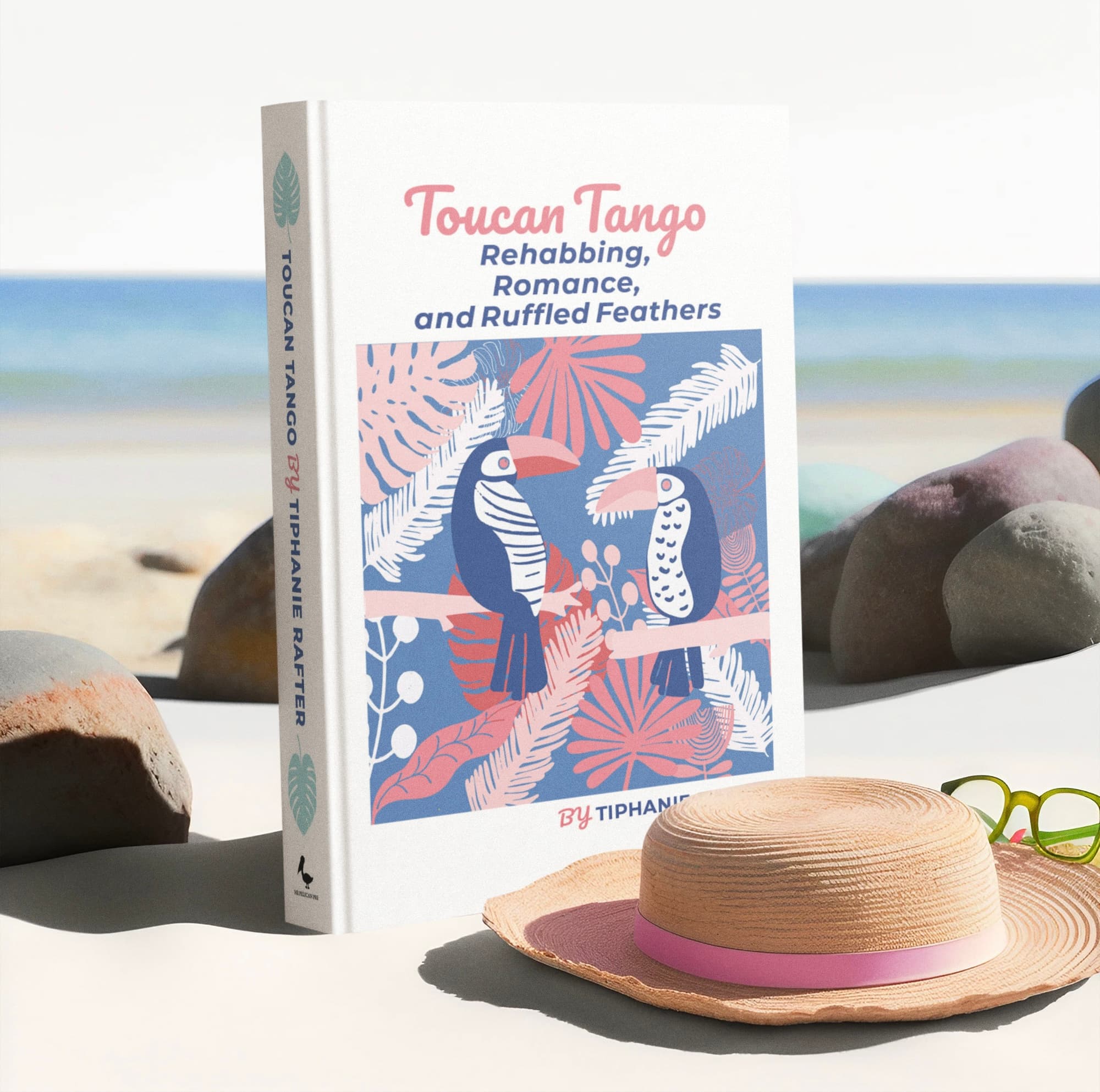 The Toucan Tango hardcover standing on white sand with a sun hat and sunglasses, the sea behind it